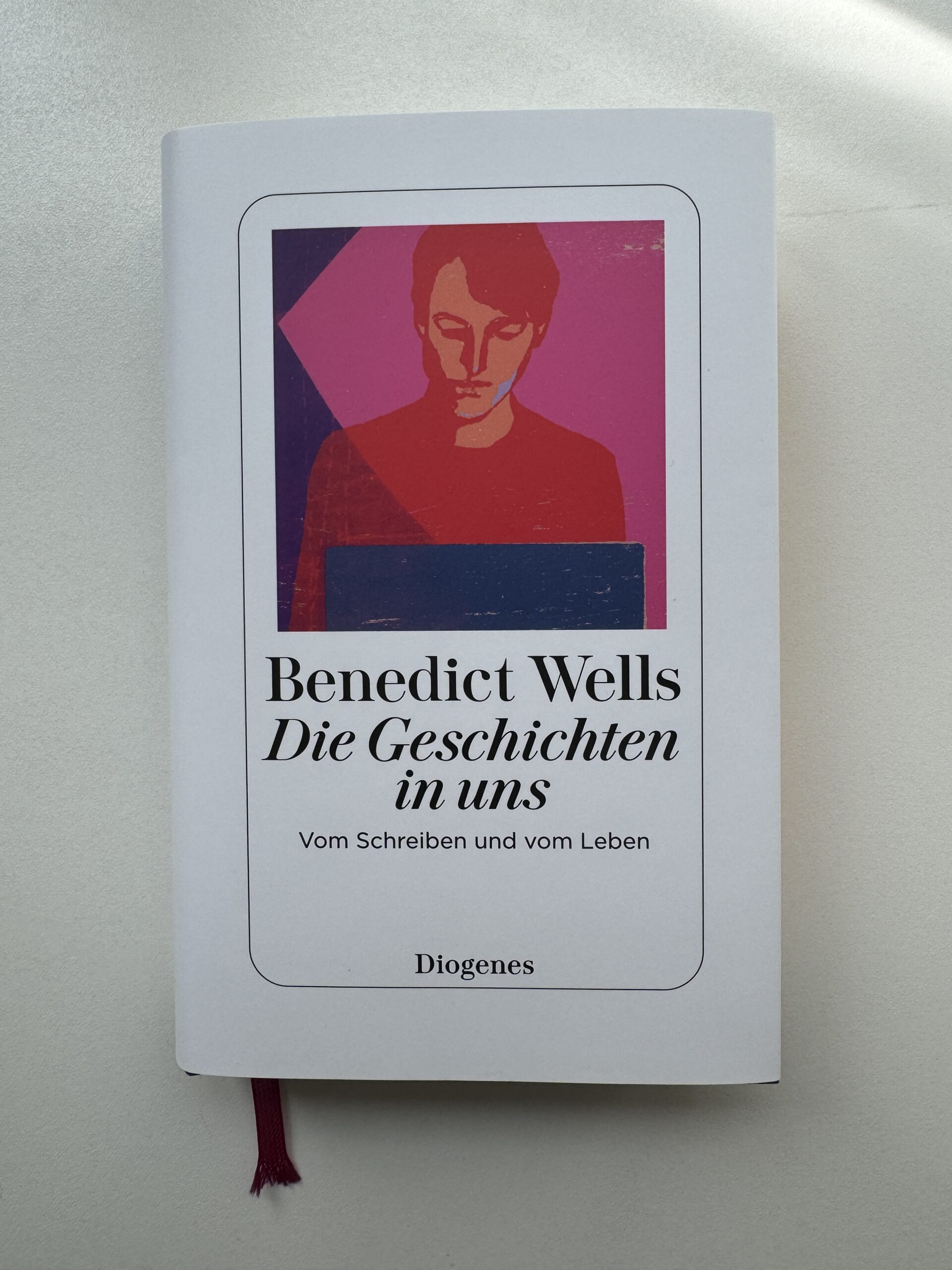 Buchcover: "Benedict Wells, Die Geschichten in uns, Vom Schreiben und vom Leben" Weißes Cover mit pinken Linolschnitt, der den Autor zeigt.