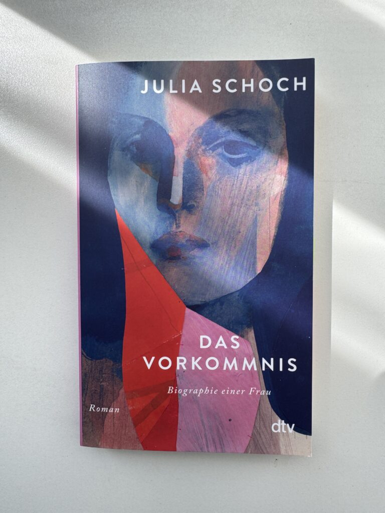 Foto des Buchs auf weißem Grund. Das Cover zeigt eine stilisiert gemalte Frau in Blau- und Rottönen.